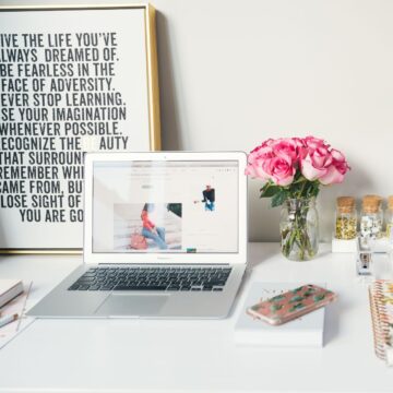 An image of a laptop on a white desk with pink accents.